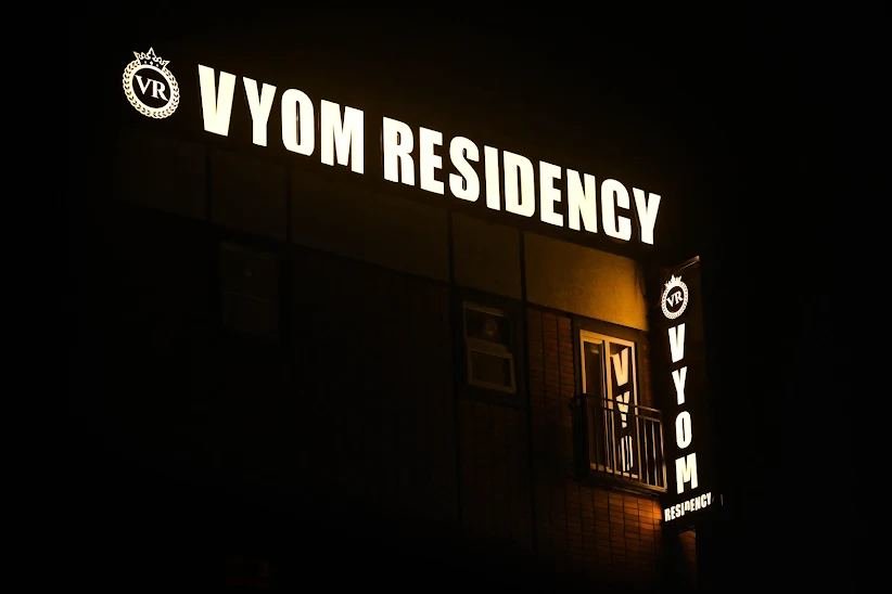 Hotel Vyom Residency signage lit up at night on the main road